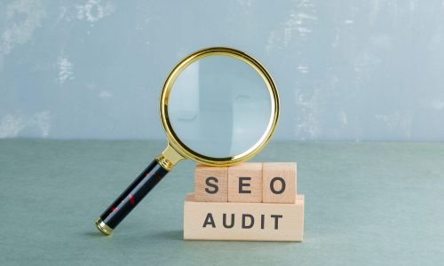 Seo analysis and business concept with wooden blocks with words on it, magnifying glass on sage color background side view. horizontal image